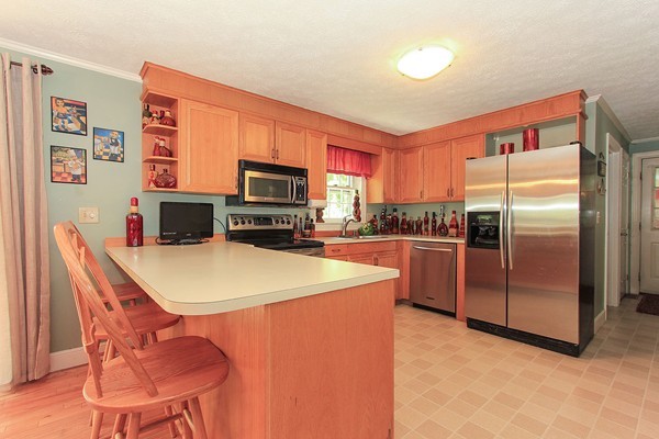230 Winding Pond Road, Unit 230 Londonderry, NH 03053 - Photo 6 of 30 a kitchen with stainless steel appliances a refrigerator a stove a sink a dining table and chairs