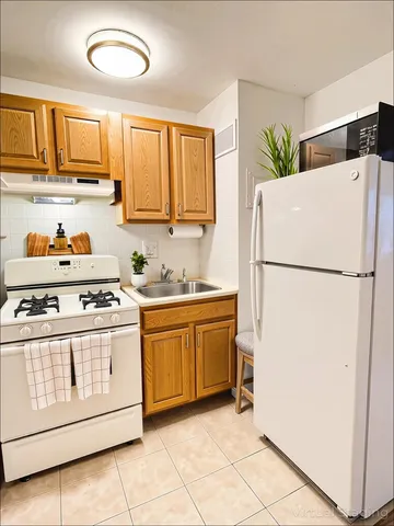 a kitchen with granite countertop a refrigerator a stove a sink and cabinets