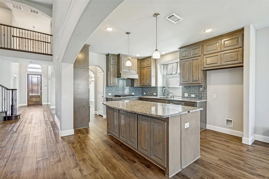 212 Wandering Way Anna, TX 75409 - Photo 11 of 36 a large kitchen with stainless steel appliances granite countertop a lot of counter space and wooden floors