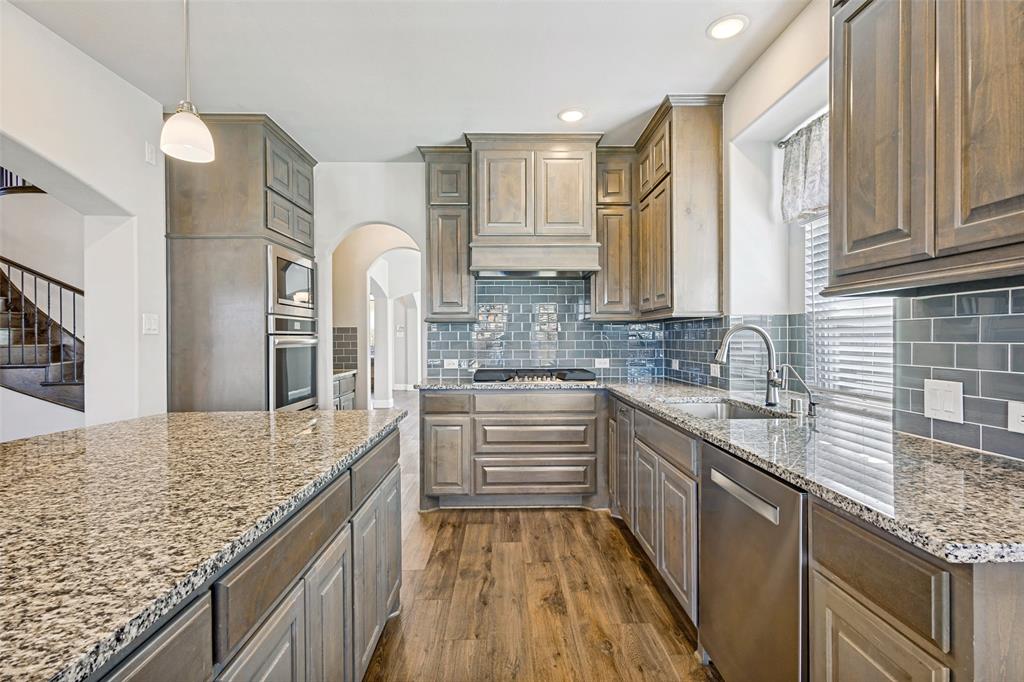 212 Wandering Way Anna, TX 75409 - Photo 14 of 36 a kitchen with stainless steel appliances granite countertop a sink stove cabinets and wooden floor