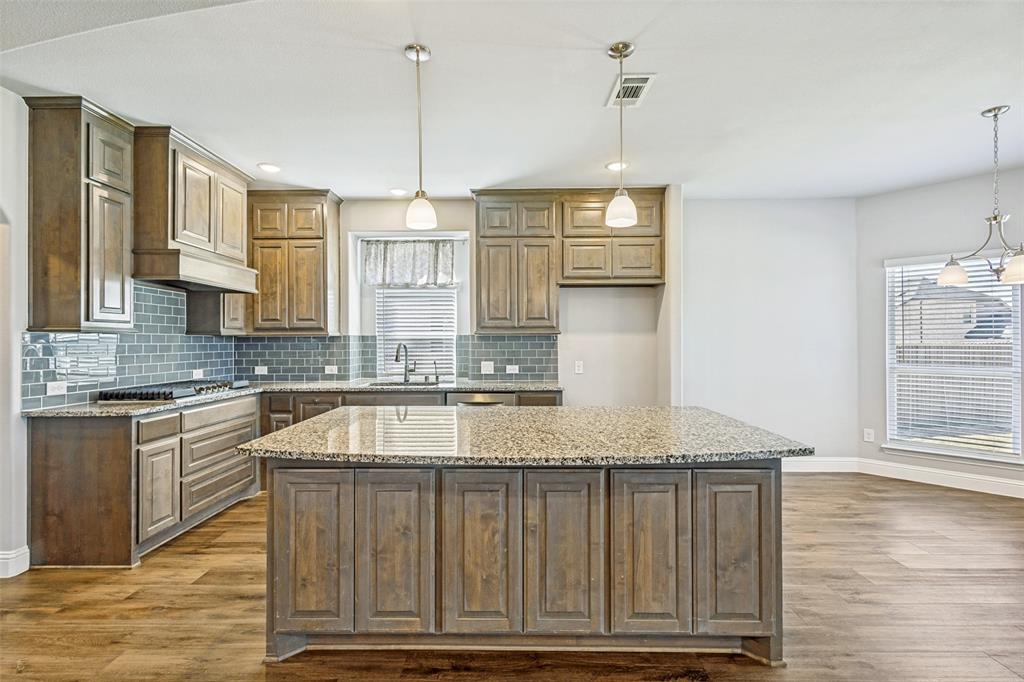 212 Wandering Way Anna, TX 75409 - Photo 10 of 36 a kitchen with kitchen island granite countertop a stove a sink and white cabinets with wooden floor