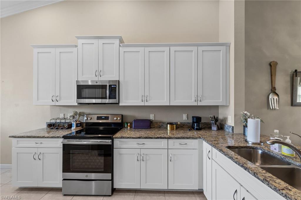 9366 Pocida Court, Unit 202 Naples, FL 34119 - Photo 9 of 44 a kitchen with white cabinets and white appliances