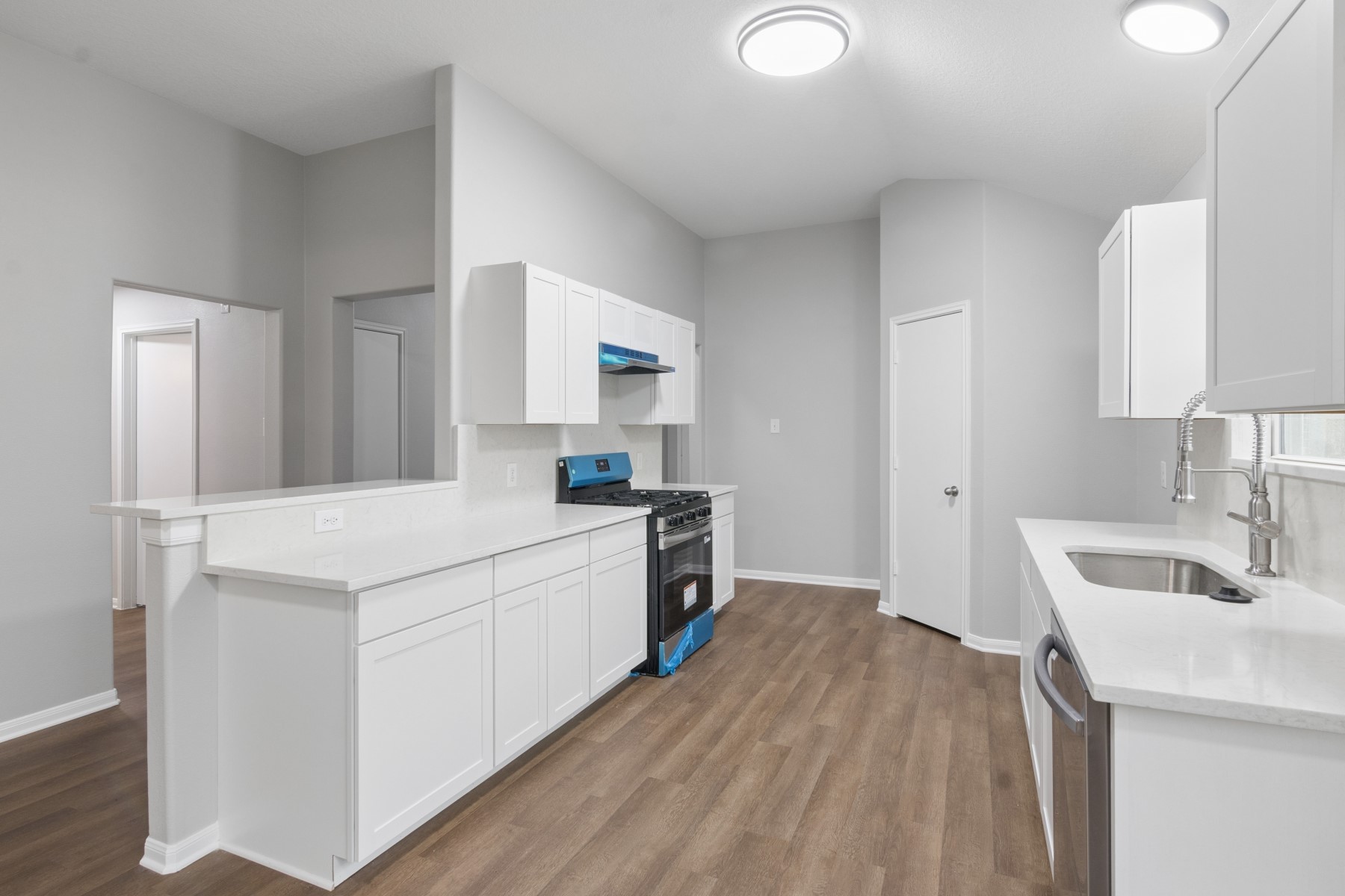 7811 Adonis Avenue Baytown, TX 77521 - Photo 16 of 36 a kitchen with a sink a stove cabinets and a wooden floor