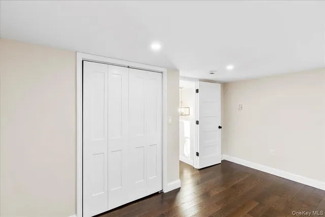 a view of an empty room with wooden floor and kitchen window