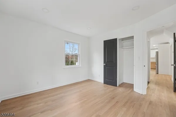 a view of an empty room with wooden floor and closet