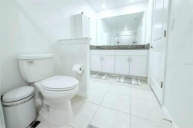 a bathroom with a granite countertop toilet sink and mirror