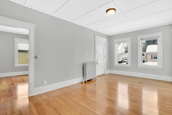 a view of an empty room with window and wooden floor