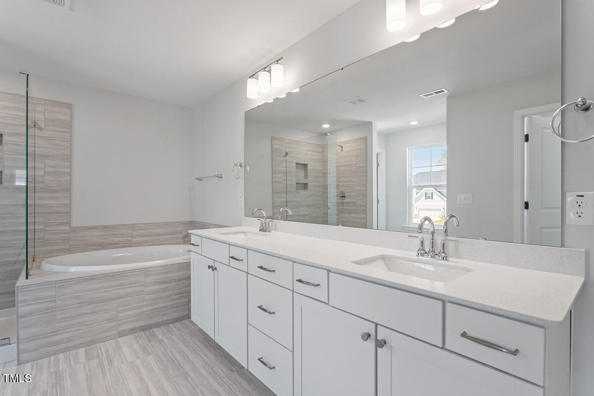 119 Augusta Pond Way, Unit 147 Raleigh, NC 27603 - Photo 15 of 37 a bathroom with a double vanity sink a mirror and a bathtub