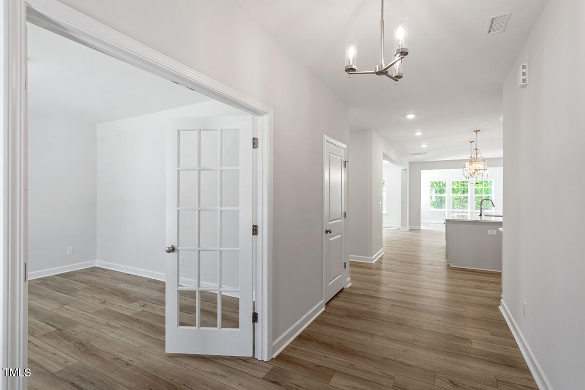 119 Augusta Pond Way, Unit 147 Raleigh, NC 27603 - Photo 4 of 37 a view of a hallway with wooden floor and chandelier