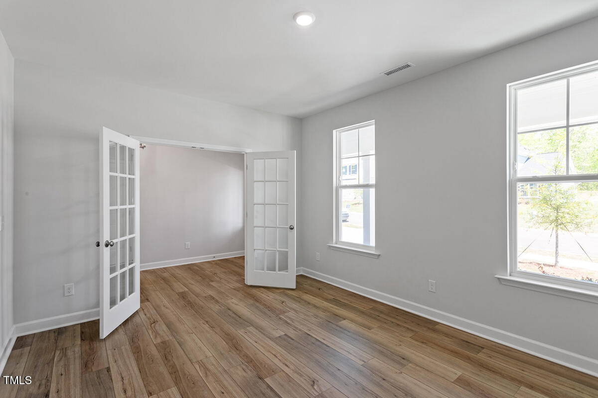 119 Augusta Pond Way, Unit 147 Raleigh, NC 27603 - Photo 5 of 37 an empty room with wooden floor and windows