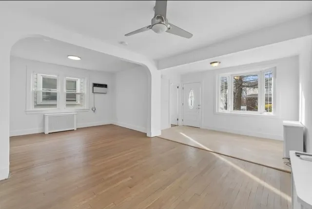 a view of an empty room with a window and wooden floor
