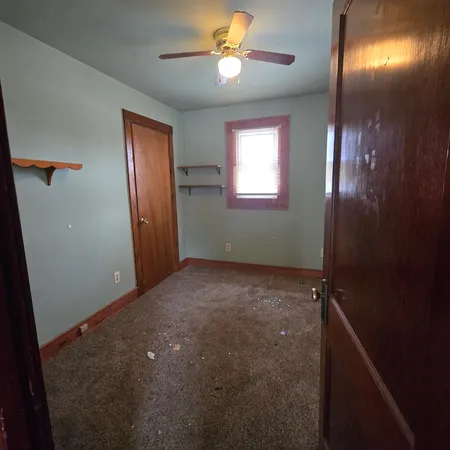an empty room with windows and fan