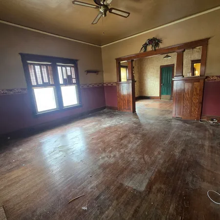 a view of empty room with wooden floor and fan