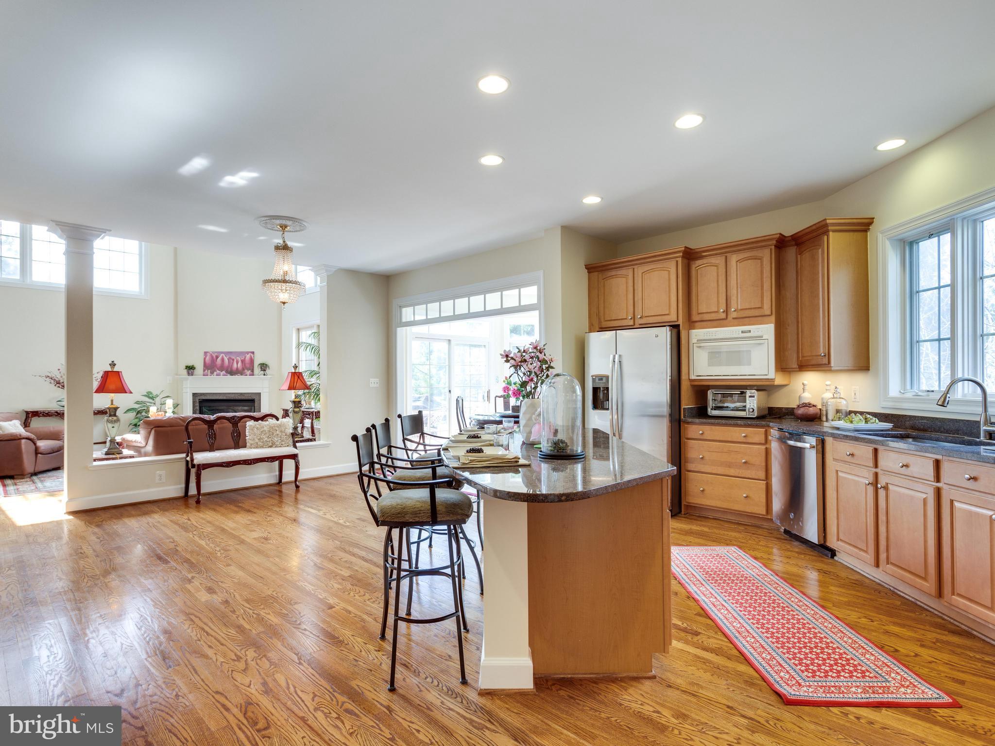 1406 Stanbridge Place Vienna, VA 22182 - Photo 8 of 30 a kitchen with stainless steel appliances kitchen island granite countertop a refrigerator a stove top oven a dining table and chairs with wooden floor