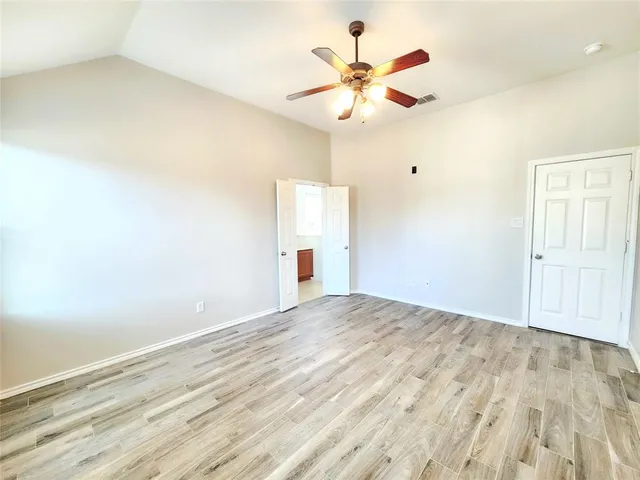 an empty room with wooden floor closet and fan
