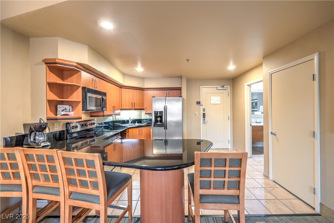 211 East Flamingo Road, Unit 1503 Las Vegas, NV 89169 - Photo 9 of 44 Kitchen with open shelves, appliances with stainless steel finishes, a peninsula, dark stone countertops, and light tile patterned flooring