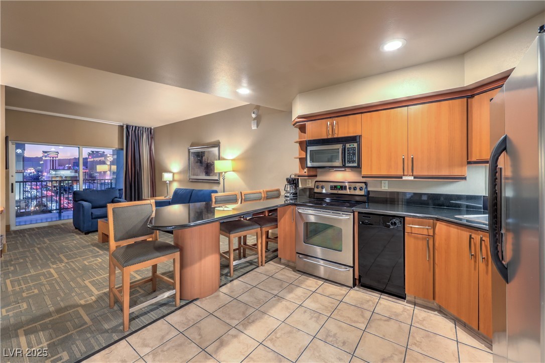 211 East Flamingo Road, Unit 1503 Las Vegas, NV 89169 - Photo 6 of 44 Kitchen featuring appliances with stainless steel finishes, a breakfast bar, brown cabinetry, open shelves, and a peninsula