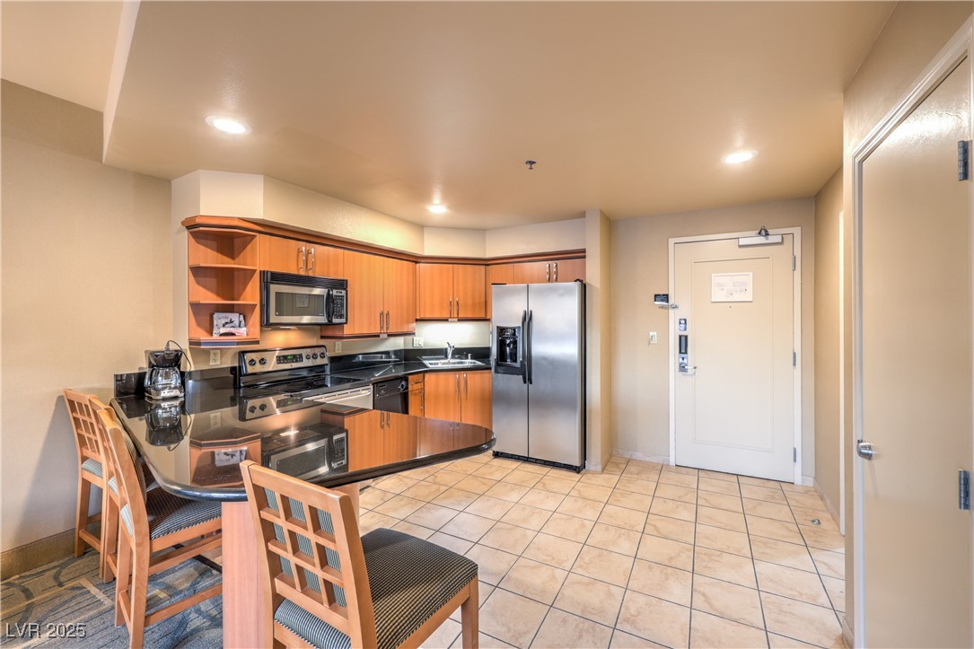 211 East Flamingo Road, Unit 1503 Las Vegas, NV 89169 - Photo 7 of 44 Kitchen featuring open shelves, stainless steel appliances, brown cabinetry, a peninsula, and a kitchen breakfast bar