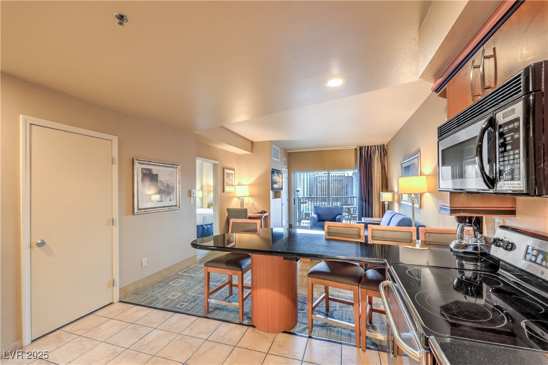 211 East Flamingo Road, Unit 1503 Las Vegas, NV 89169 - Photo 44 of 44 Kitchen featuring stainless steel range with electric stovetop, a peninsula, open floor plan, a kitchen breakfast bar, and light tile patterned flooring