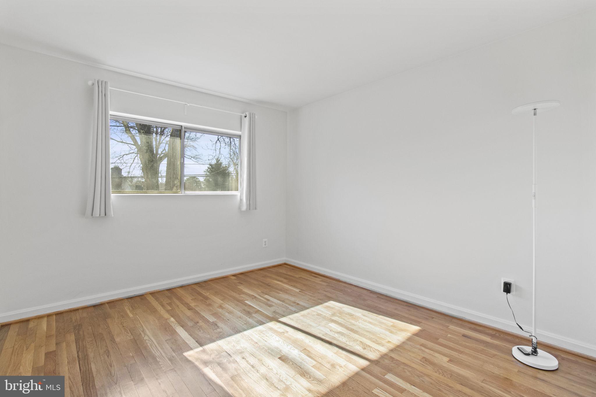 9703 Singleton Drive Bethesda, MD 20817 - Photo 14 of 22 an empty room with wooden floor and windows