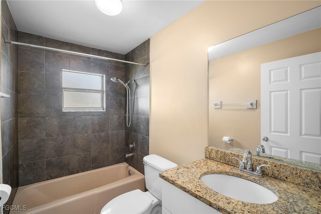 5539 Tenth Avenue Fort Myers, FL 33907 - Photo 16 of 20 a bathroom with a granite countertop bathtub shower sink vanity mirror and toilet