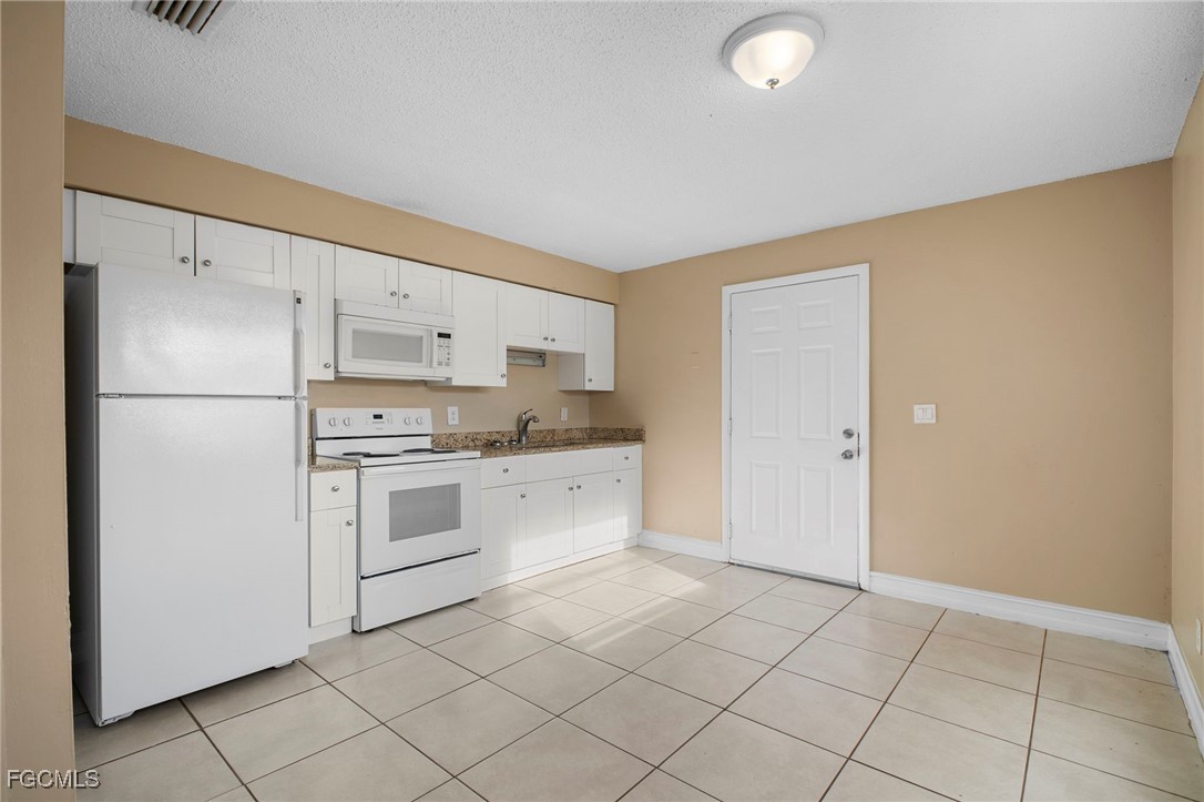 5539 Tenth Avenue Fort Myers, FL 33907 - Photo 9 of 20 a kitchen with white cabinets and white appliances