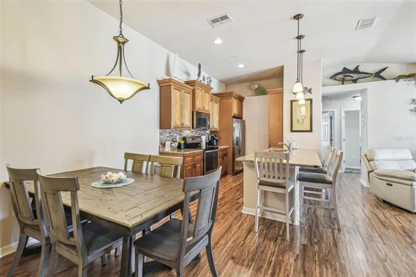 a kitchen with granite countertop a stove a sink a dining table and chairs with wooden floor
