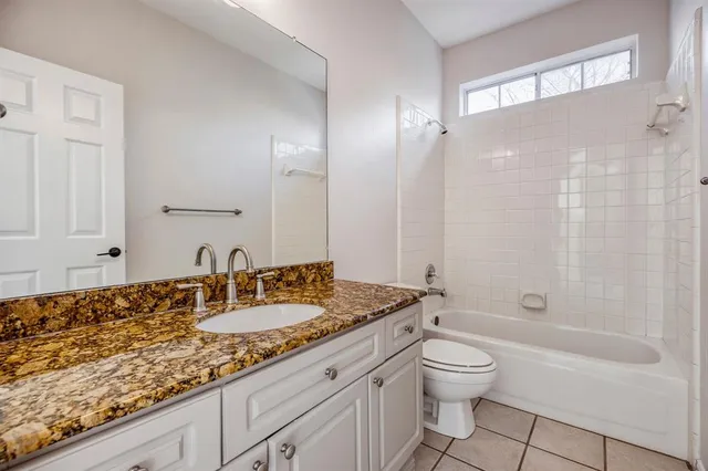 a bathroom with a granite countertop sink a toilet and shower