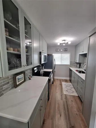 a large kitchen with stainless steel appliances a large counter top a stove and a sink