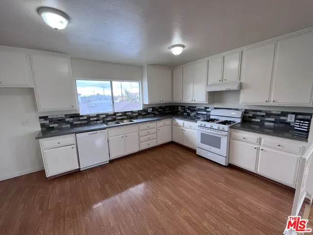 a kitchen with granite countertop wooden floors and white cabinets