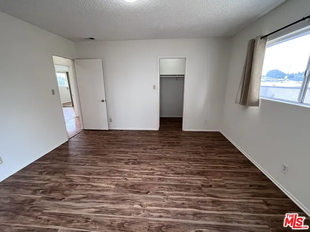a view of an empty room with wooden floor and window