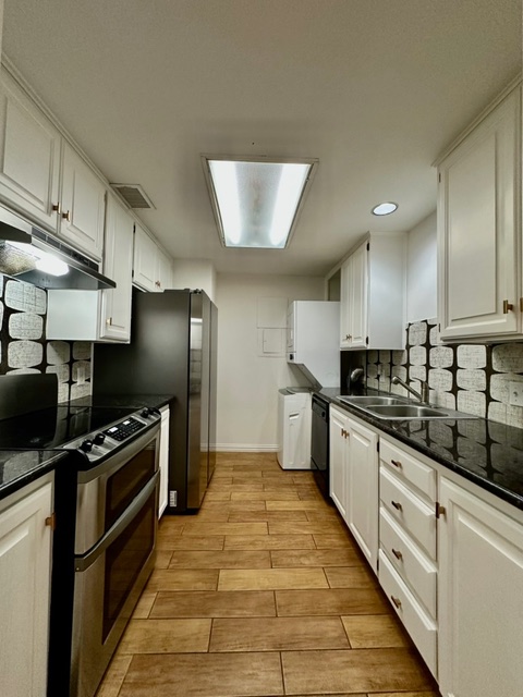 Streamlined kitchen features wood-look tile flooring and sleek appliances, perfect for everyday culinary tasks.
