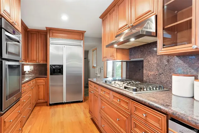 a kitchen with stainless steel appliances granite countertop a refrigerator and a stove top oven