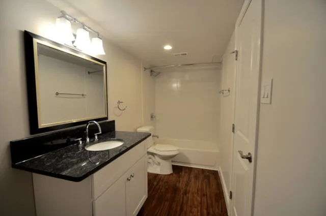 a bathroom with a sink a toilet a mirror and shower