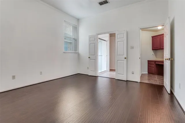 an empty room with wooden floor chandelier and windows