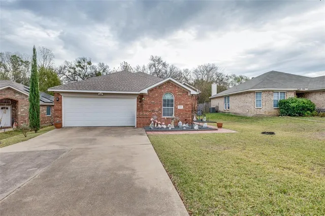 a front view of house with yard and trees in the background