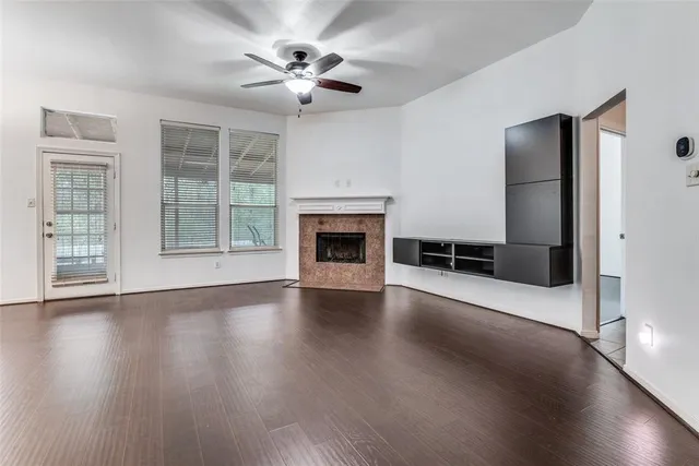 an empty room with wooden floor fireplace and windows