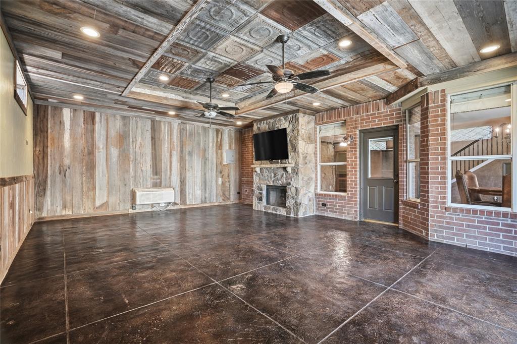 2133 Rustic Ridge Drive Keller, TX 76248 - Photo 34 of 40 Unfurnished living room featuring wood walls, a fireplace, and a ceiling fan