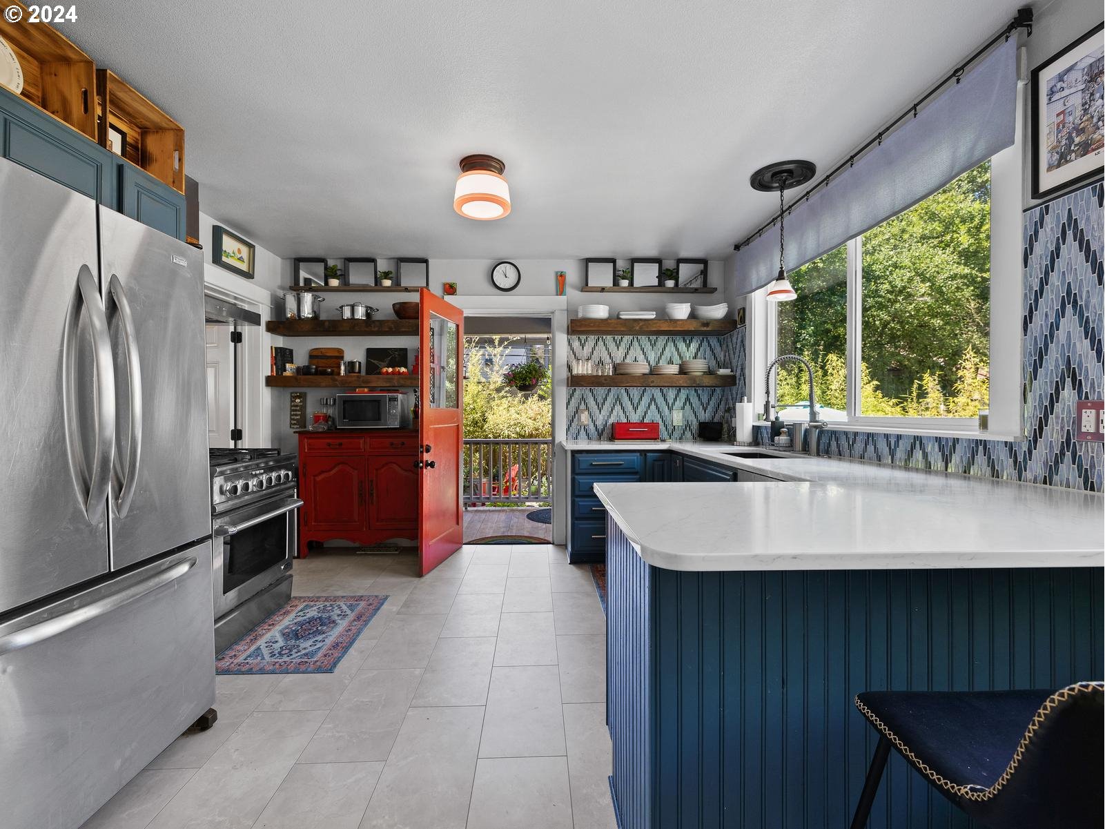 2306 Northeast Couch Street Portland, OR 97232 - Photo 13 of 48 a kitchen with stainless steel appliances kitchen island granite countertop a refrigerator a stove and a sink with wooden floor