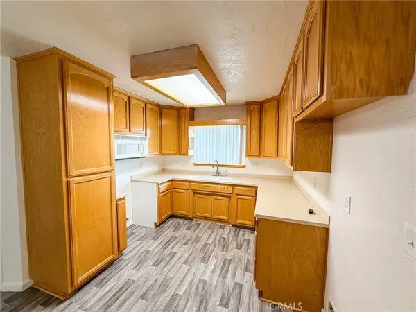 a kitchen with stainless steel appliances granite countertop a refrigerator a sink dishwasher and wooden cabinets with wooden floor