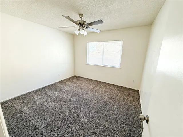 an empty room with a window and a fan