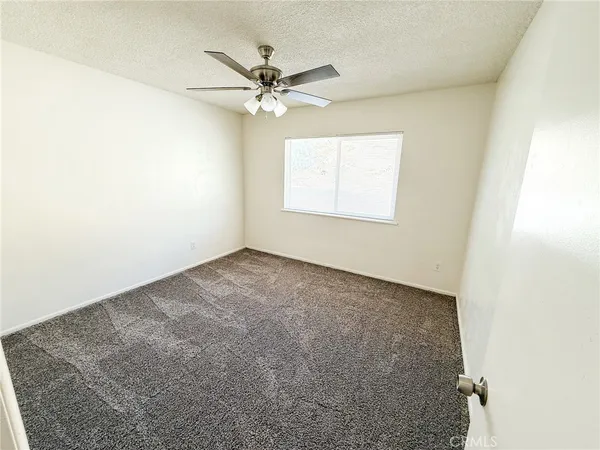 an empty room with a window and a fan