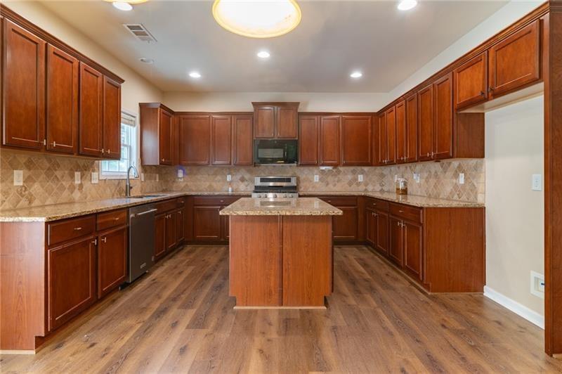 206 Sawtooth Court Canton, GA 30114 - Photo 9 of 42 a kitchen with wooden floors wooden cabinets a sink and a stove