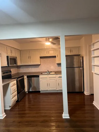 a kitchen with granite countertop a refrigerator stove and wooden floor