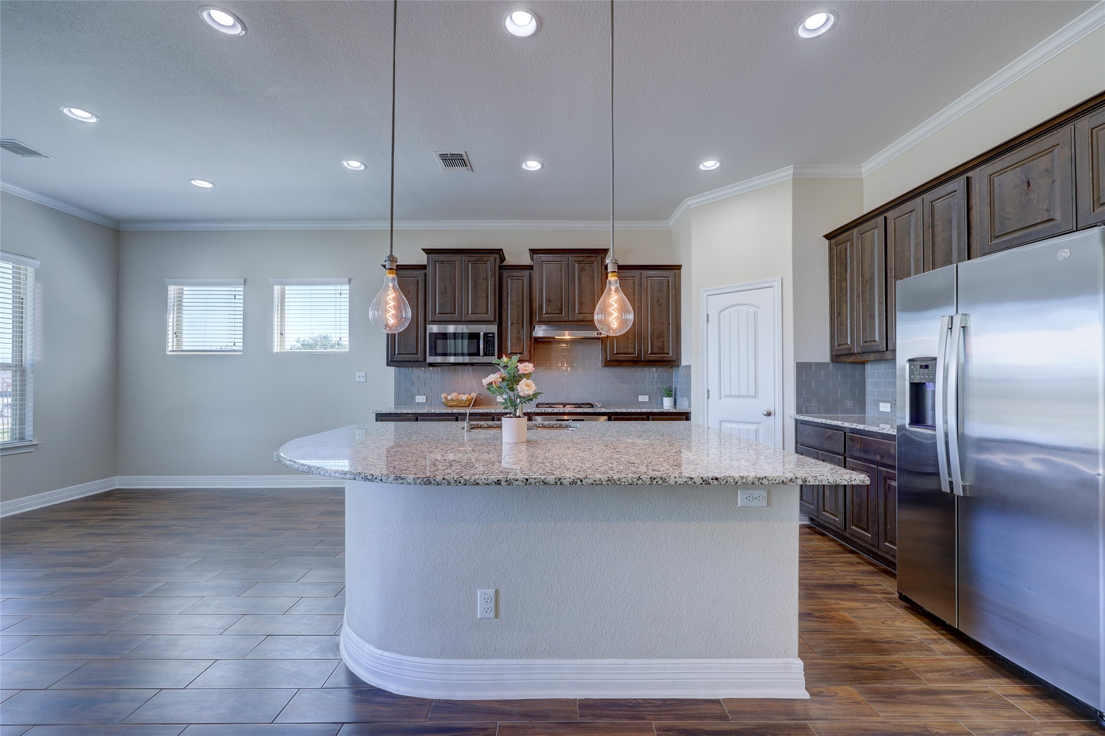 409 Betony Loop Buda, TX 78610 - Photo 9 of 38 A well-appointed kitchen showcasing a spacious island with granite counters, perfect for culinary endeavors and casual dining.