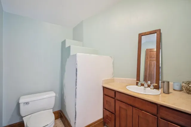 a bathroom with a granite countertop sink toilet and mirror