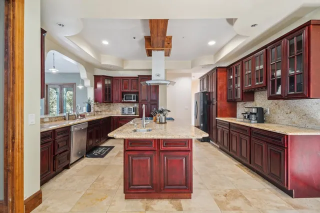 a kitchen with kitchen island granite countertop a sink stove and cabinets