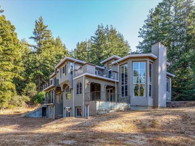 a view of a white house with large windows and a small yard