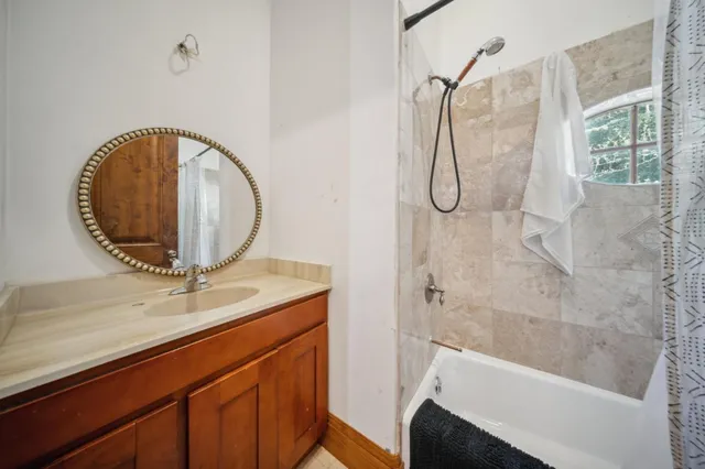 a bathroom with a granite countertop sink a mirror and shower