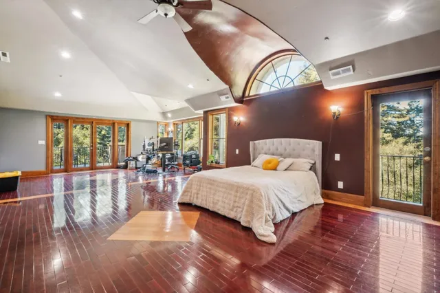 a spacious bedroom with a large bed and wooden floor